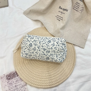 Top view of blue floral makeup bag on a woven mat with vintage props in bright setting
