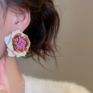 Gros plan de boucles d'oreilles fleur 3D blanches élégantes avec bords dorés et pistils