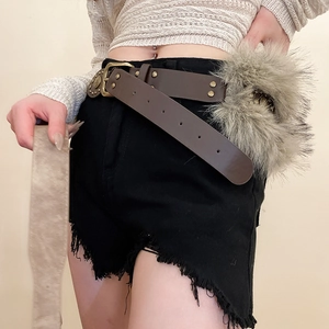 Détail de ceinture en cuir vintage avec clous en laiton et pendentif en fausse fourrure