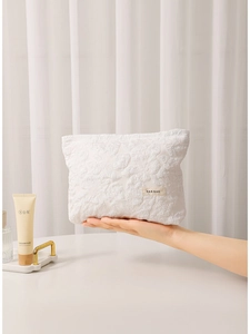 White floral embossed makeup bag with H&R logo tag held by hand for scale display