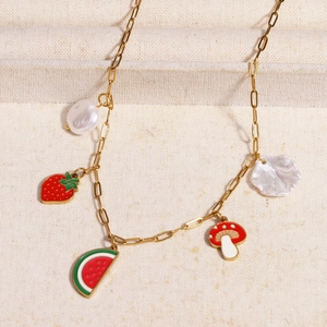 Detailed shot of titanium steel necklace with fruit charms and baroque pearls on linen