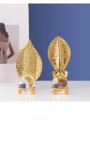 Detailed view of golden metal leaf statues with intricate veins and crystal ball base