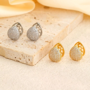 Pave zircon teardrop earrings in 18K gold and silver plating on stone background