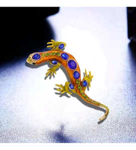 Detail of lizard brooch with orange enamel, blue gemstones, and green rhinestones