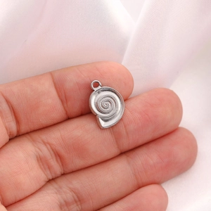 Macro shot of silver conch shell charm with swirl texture and bead detailing
