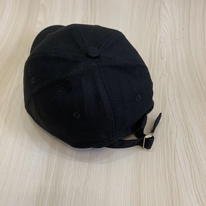 Detail of black cotton baseball cap with silver metal adjustable buckle and back strap