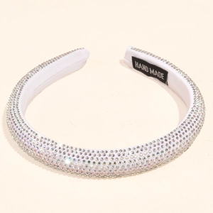 Detail of a thick white headband with hand-set rhinestones and a hand-made label