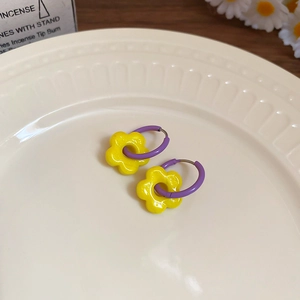 Detail of purple hoops and bright yellow daisy flower charms on a ceramic plate