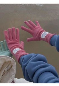 Detail of pink knitted wool gloves with ribbed cuffs and white woven labels for winter