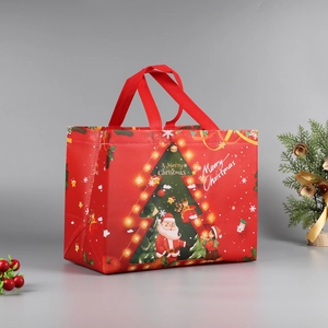 Detailed view of red Christmas non-woven gift bag with Santa Claus and tree patterns