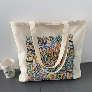Detail of embroidered canvas tote bag with colorful patterns like palms and musical notes