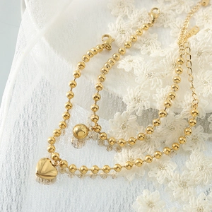 Vintage 18K gold plated bead bracelet with heart and ball pendants on lace background