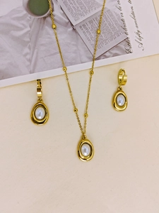 Flat lay of vintage gold jewelry set with teardrop pearl pendants and beaded chain