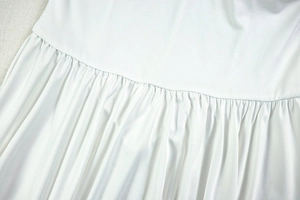 Close-up of white backless dress showing refined pleating and stitching details