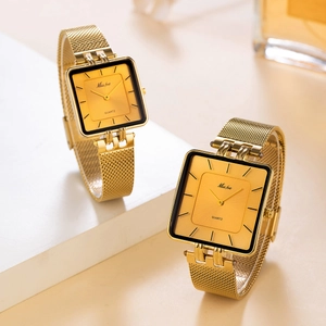 Macro view of gold square quartz watches with Milanese mesh strap on elegant background