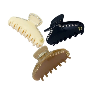 Dettaglio di tre mollette per capelli in acetato con strass e logo D dorato in vari colori
