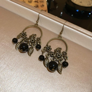Détail de boucles d'oreilles vintage en bronze avec perles noires sur un plateau