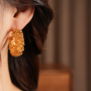 Detailed close-up of 24k gold-plated woven texture hoop earrings on model ear