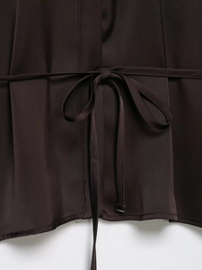 Detail of chocolate brown satin fabric featuring a waist belt tied in a bow