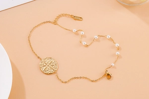 Detail of gold stainless steel bracelet with star charm and white pearl accents