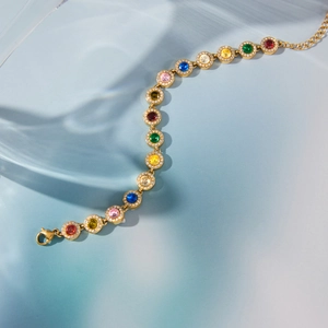 Elegantes goldenes Herzarmband mit Regenbogen-Zirkonia auf einem sanften blauen Hintergrund