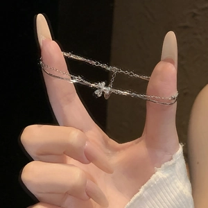 Close-up of a silver double-layered bracelet with a sparkling zircon bow pendant