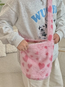 Plush pink bucket bag with heart pattern and wide shoulder strap shown on model