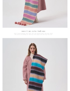 Detail of colorful rainbow striped scarf featuring soft texture and pink pompom accents