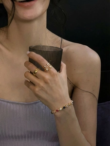 Detail of gold-plated star rings and colorful gemstone bracelet worn by a model