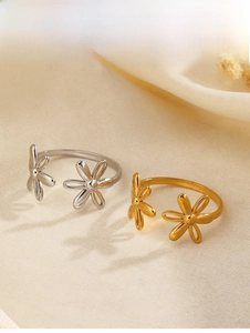 Detailed close-up of gold and silver flower open rings with adjustable bands on fabric
