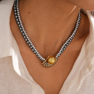 Dettaglio collana di perle grigie a doppio strato con ciondolo dorato vintage