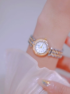 Close-up of two-tone metal watch with rhinestone bezel on a woman's wrist