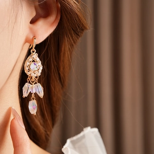 Close-up of vintage golden drop earrings with white pearls and iridescent crystal tassels