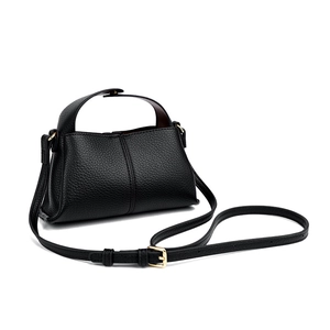 Detail of black lychee grain leather handbag featuring gold buckles and adjustable strap