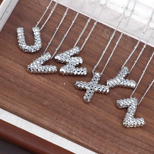 Detailed close-up of silver-tone alphabet pendants U to Z with faceted metal texture