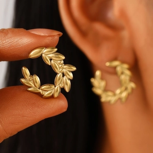 Detailed macro view of olive leaf gold earrings with vintage matte finish and C-shape design