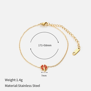 Makroaufnahme eines goldfarbenen Edelstahlarmbands mit einem Kleeblatt-Charm und Kristallen