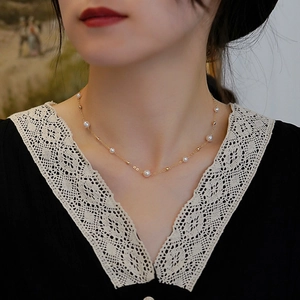 Detail of elegant gold pearl necklace worn by a model in a black lace v-neck dress