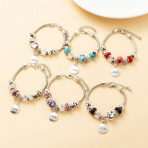 Flat lay of colorful beaded bracelets with Love charms on silver snake chains