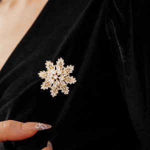 Detailed close-up of a snowflake brooch with zircon crystals on a dark velvet garment
