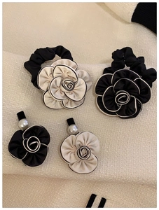 Detail of camellia hair accessories set with pearls on elegant tweed background