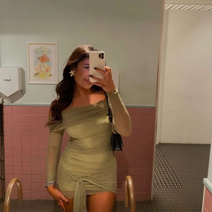 Détail de la robe moulante vert olive avec fronces, épaules dénudées et lien à la taille