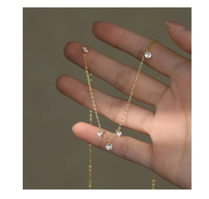 Detail showing hand holding gold necklace with multiple round sparkling zircon pendants