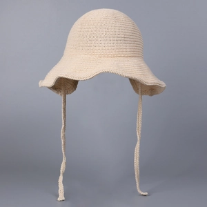 Detailed view of cream knit bucket hat with wavy brim and matching woven tie straps