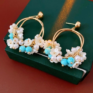 Detail of floral earrings with turquoise beads on a green textured jewelry box