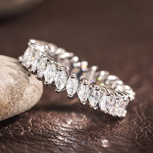 Macro detail of marquise-cut white crystals set in a polished silver eternity band