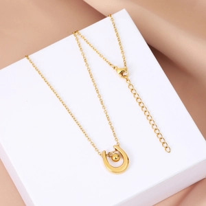 Detail of gold U-shaped pendant with polished bead and adjustable lobster clasp chain