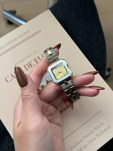 Primo piano di un orologio quadrato da donna in acciaio oro e argento su sfondo di libri