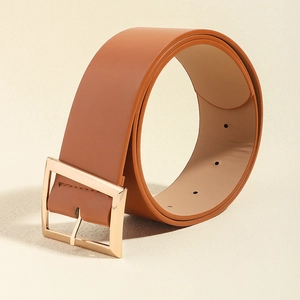 Close-up of a brown leather belt with a polished golden square buckle on beige surface