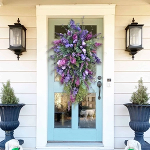 Teardrop tulip wreath with purple flowers and green leaves on a light blue front door